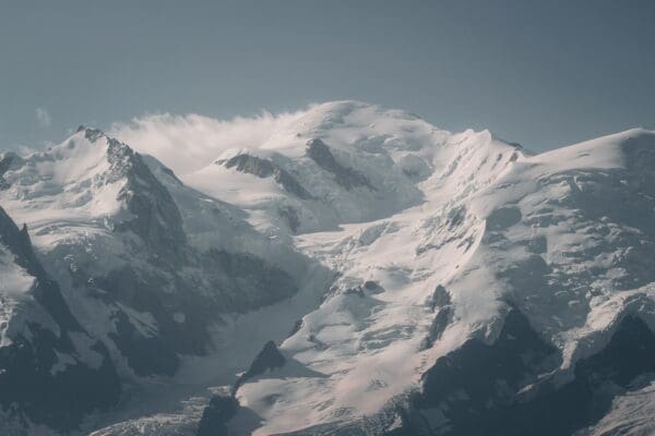 a mountain range covered in snow under a blue sky